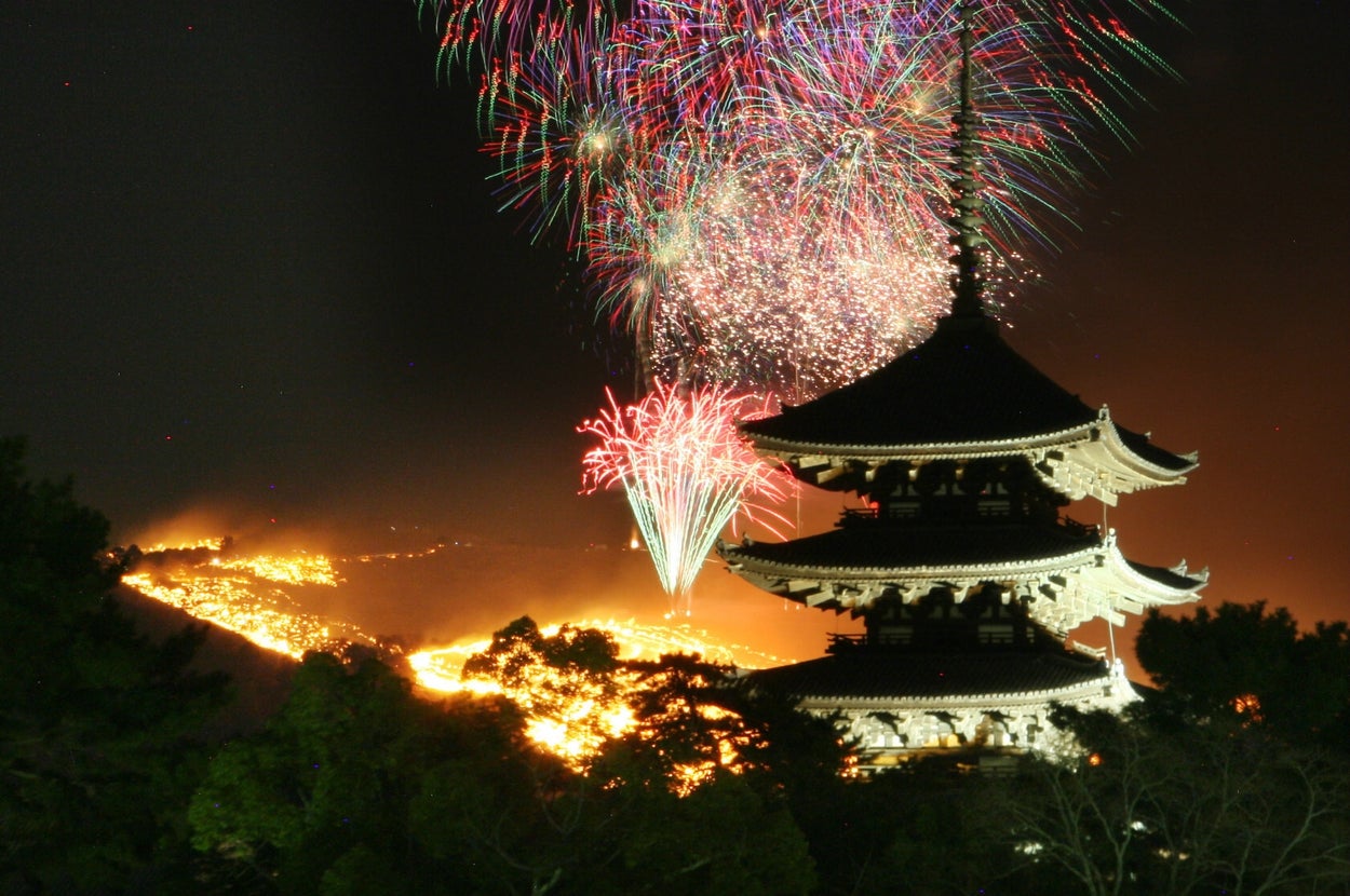 花火が夜空に輝き、寺院の五重塔が背景にある壮大な風景。