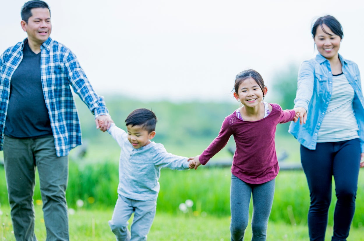 家族が手をつないで屋外を楽しんでいる様子。子供たちは笑顔で、両親は彼らを見守っています。