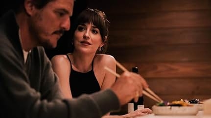 A woman in a black top sits at a table with a man, holding chopsticks. They appear to be sharing a meal in a cozy setting