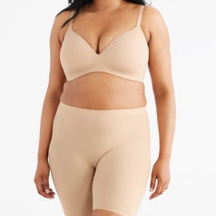 A person is wearing a seamless, nude-toned bra and shorts set, showcasing comfortable shapewear suitable for everyday use