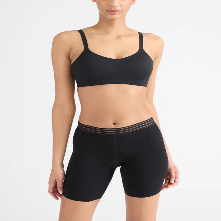 Person modeling streamlined black workout attire, including a sports bra and spandex shorts