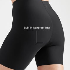 Person wearing high-waisted black bike shorts with text pointing to a built-in leakproof liner