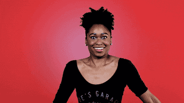 Woman with an excited expression doing jazz hands against a plain background
