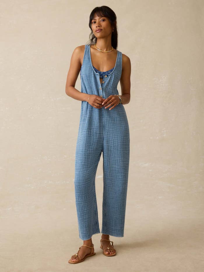 Model wearing a sleeveless, textured indigo jumpsuit with a scoop neckline