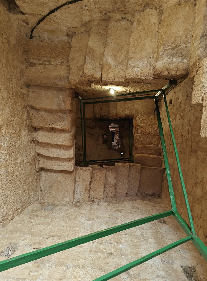 Stone staircase spirals downward successful  an ancient, constrictive  passageway. Green beams are installed for support