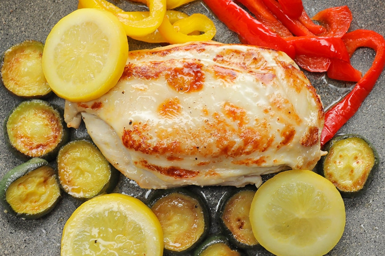 フライパンで調理された鶏の胸肉とズッキーニ、レモン、パプリカの料理。