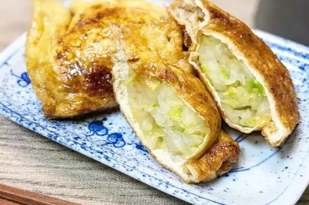 皿に載った揚げ餃子の中身が見える。キャベツが具材として詰められている。横に箸が置かれている。