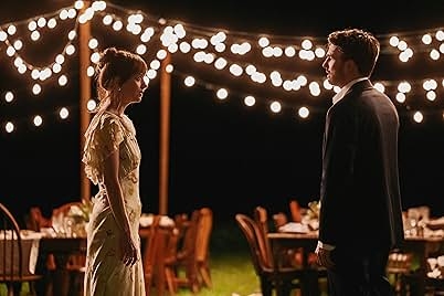 Two people stand facing each other outdoors at night, surrounded by string lights and empty tables