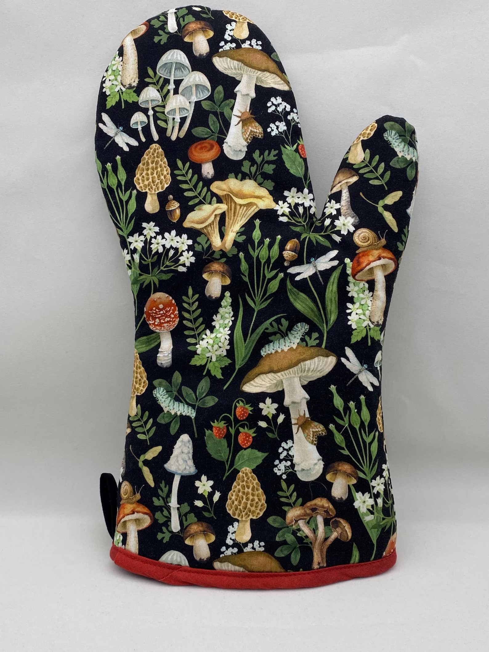Oven mitt with a whimsical print of various mushrooms and small flowers, ideal for kitchen use