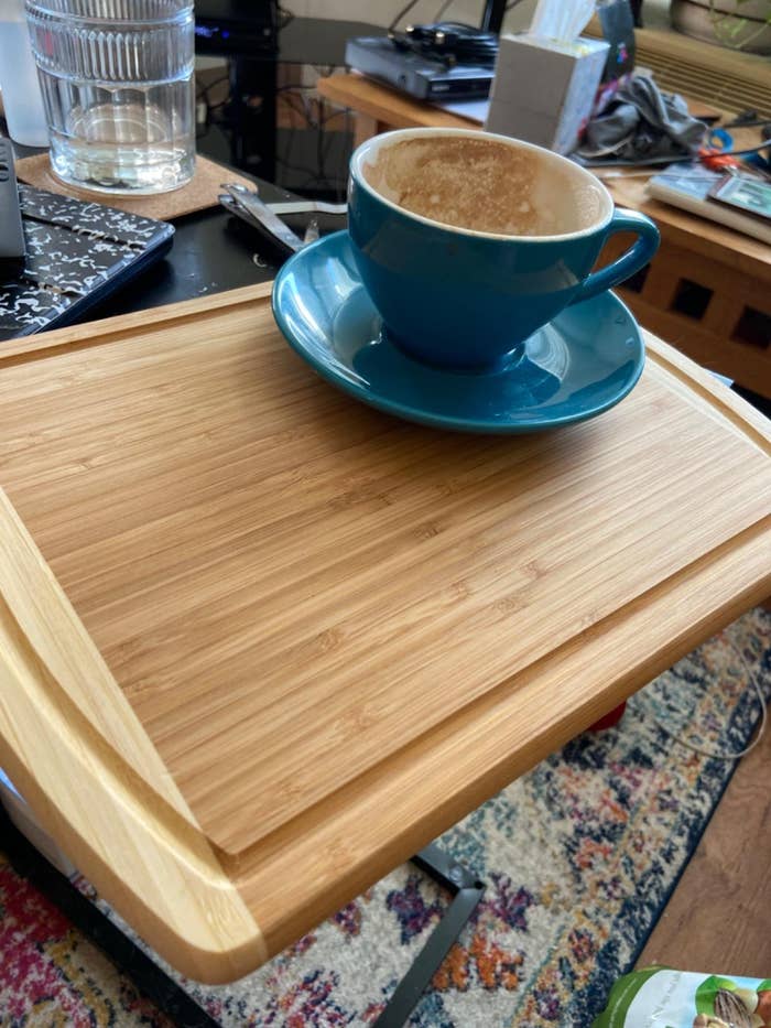 Revviewer's photograph of a bamboo cutting committee with a bluish java cupful connected a saucer connected it, situated successful a cozy room abstraction with assorted items successful the background