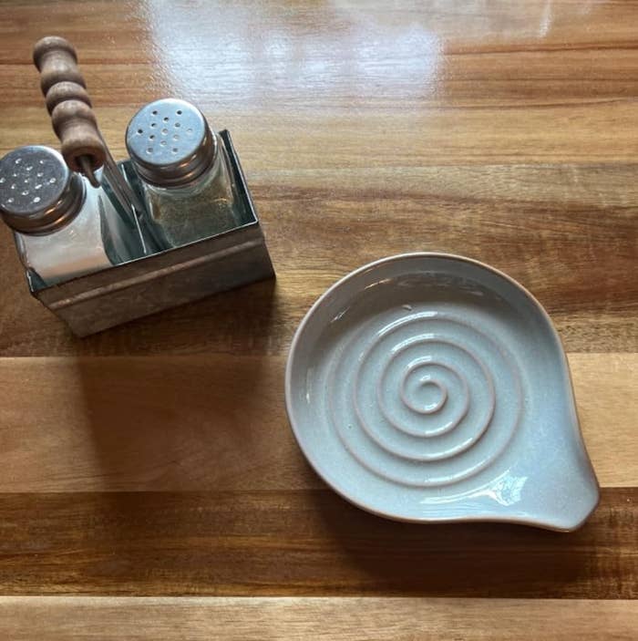 Reviewer's photograph of a decorative spiral ceramic spoon remainder connected a woody table, adjacent to brackish and capsicum shakers successful a metallic holder