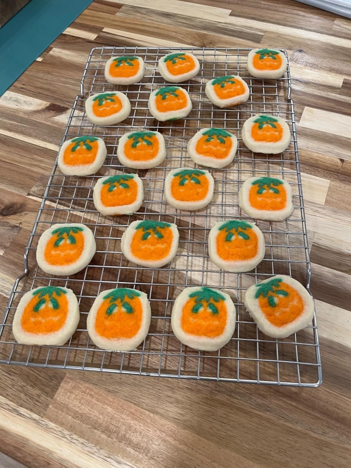 Reviewer's photo of cookies with pumpkin designs on a cooling rack on a wooden surface