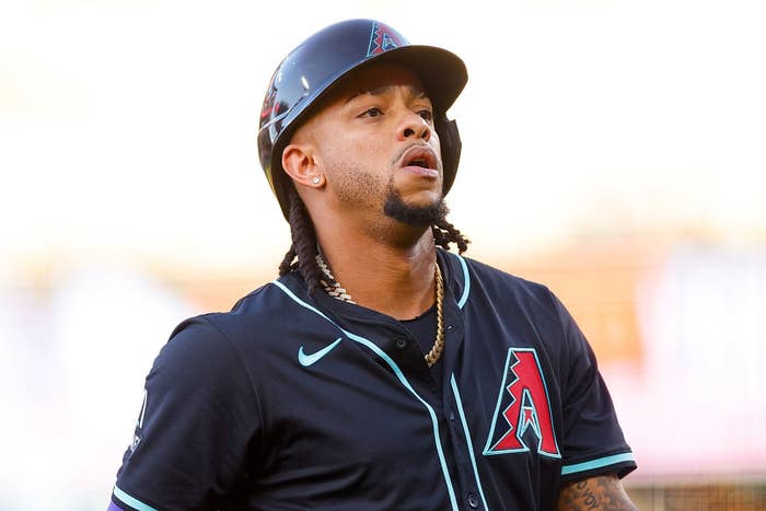 A baseball player wearing a helmet and team uniform is on the field during a game, showing a focused expression