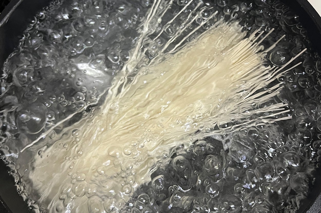 鍋で沸騰するお湯に入れられたそうめん。