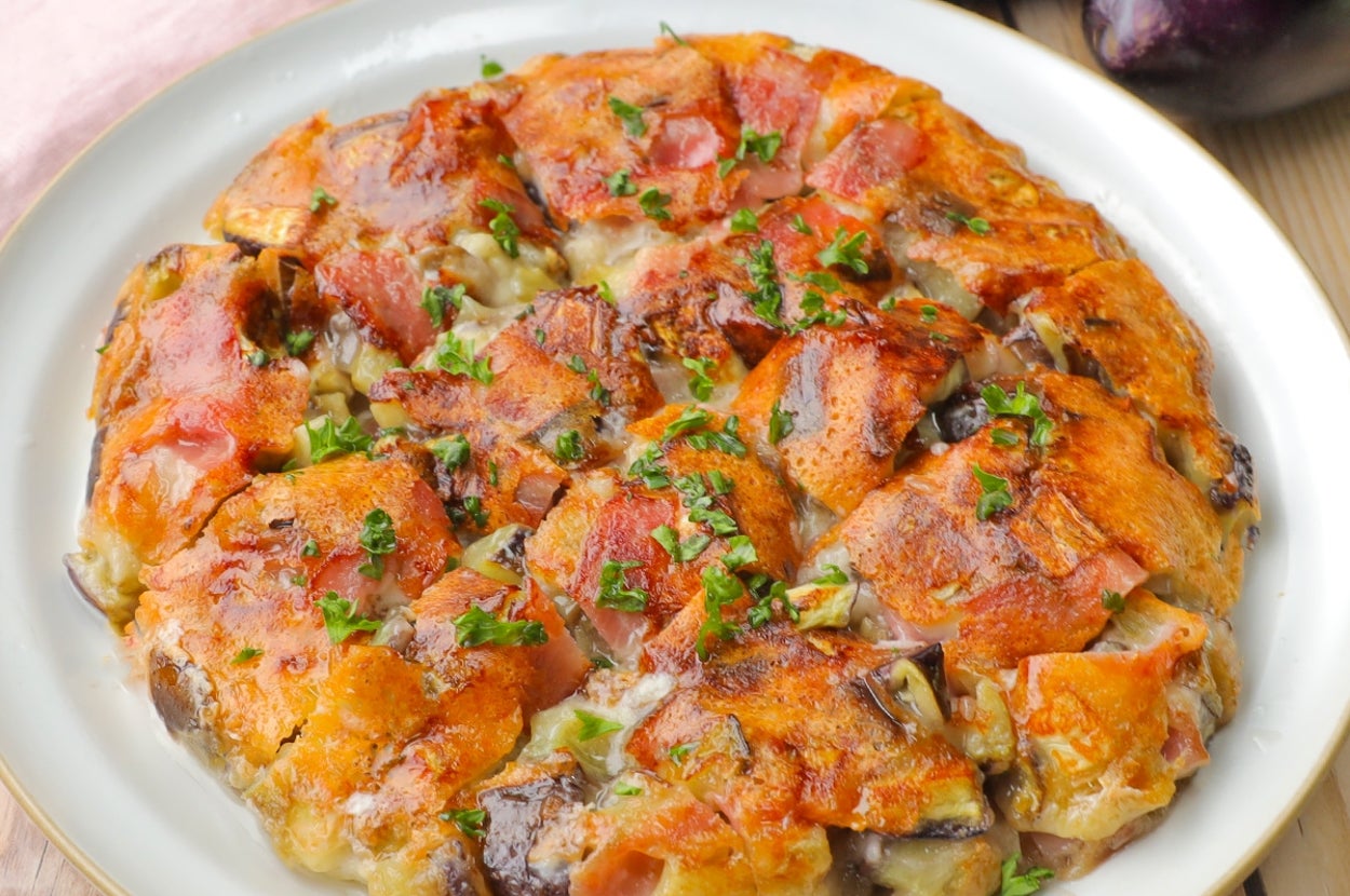 皿に盛られた焼きナスのグラタン。トマトやチーズがトッピングされ、パセリが散りばめられている。
