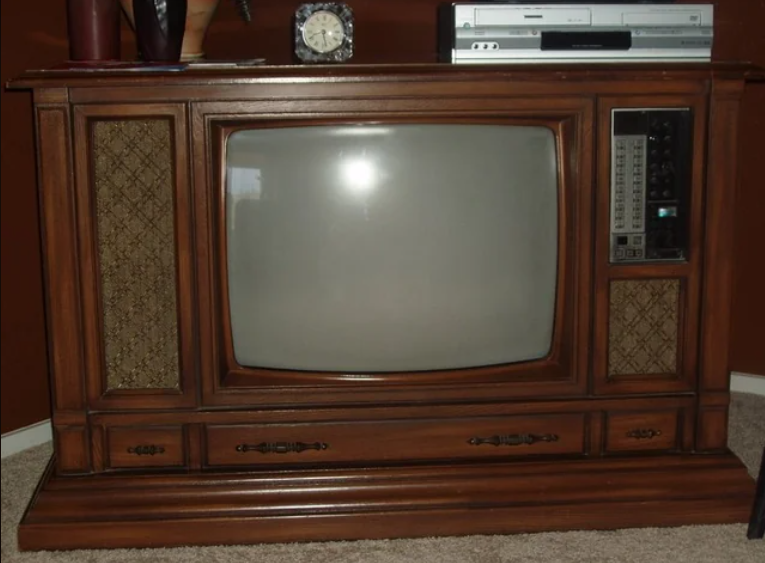 Vintage woody console TV with knob controls and a VHS subordinate connected top