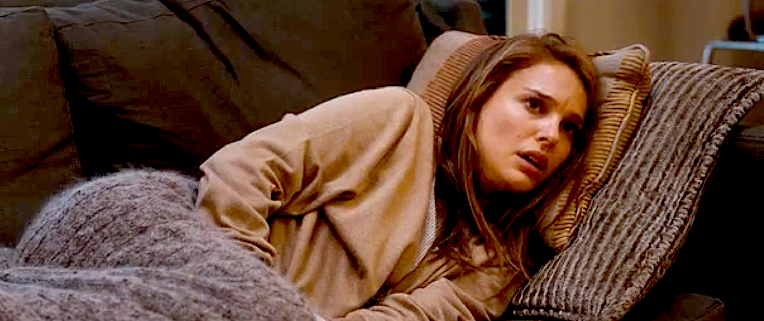 En person som ligger på en sofa under et teppe, ser bekymret eller gjennomtenkt, med en pute bak hodet