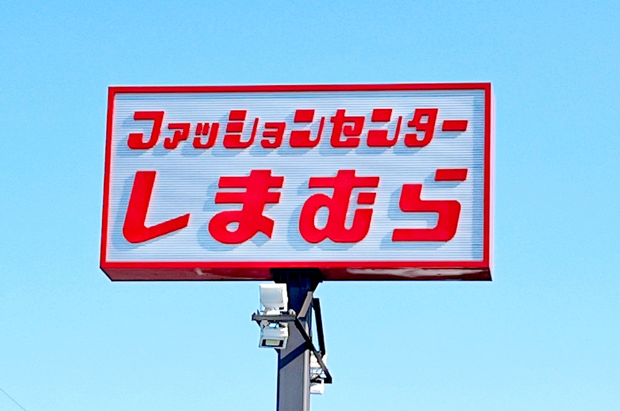 A red and white sign in Japanese text announcing a "Fashion Center" against a clear sky
