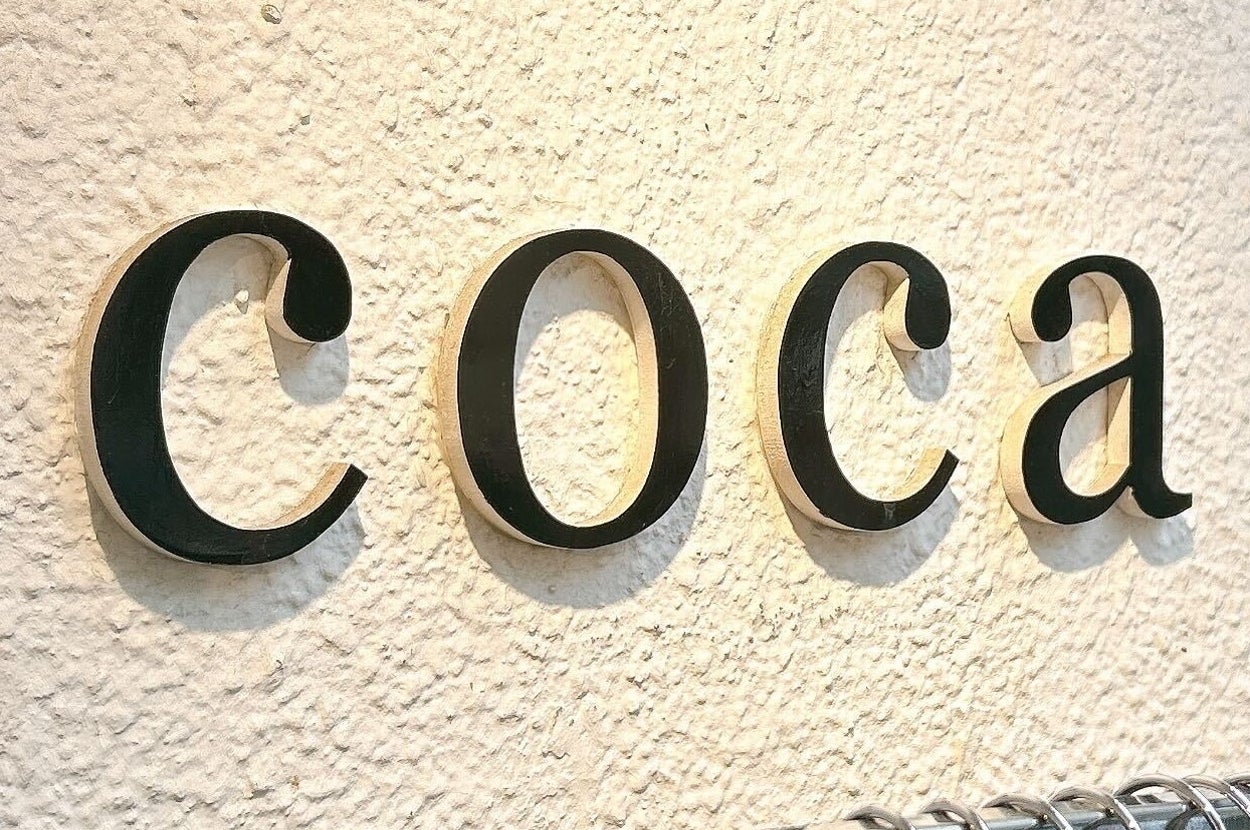 壁に取り付けられた「coca」という文字と、服が並んだハンガーラック。