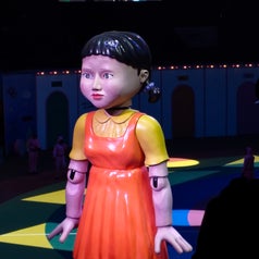 Large robot girl statue on stage with audience in background during a performance