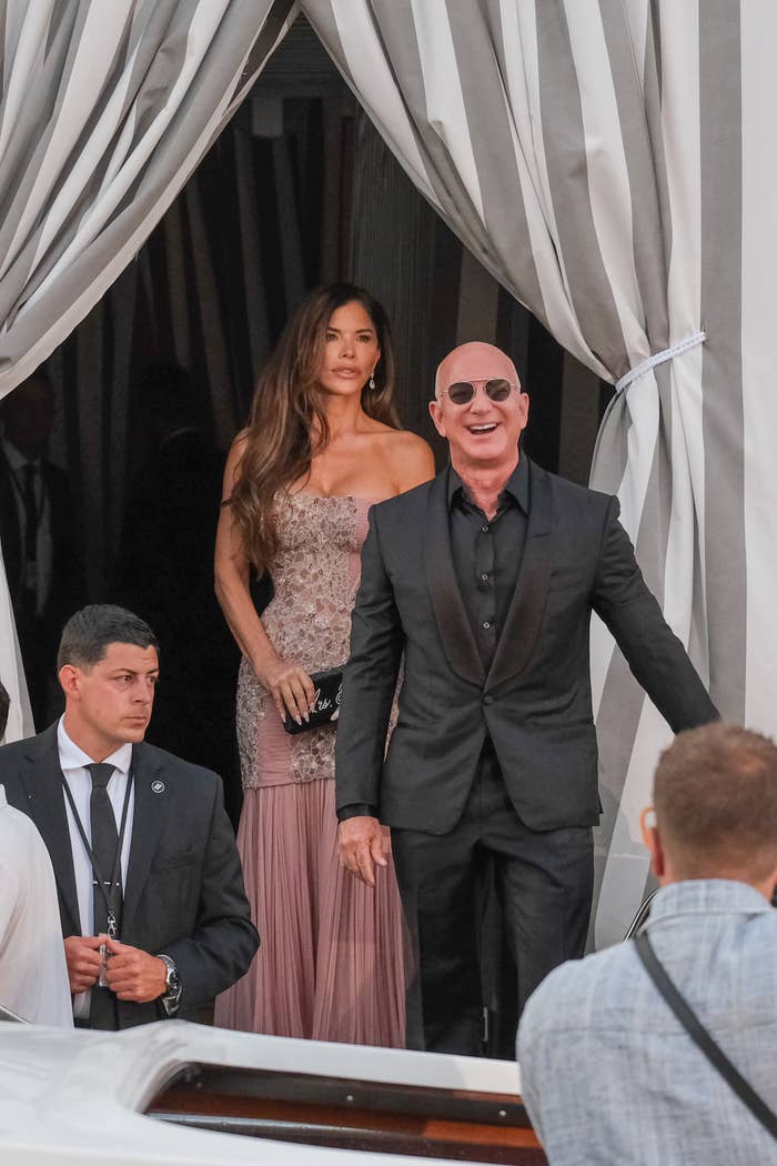 A mates successful ceremonial attire exits an event. The antheral wears a sleek suit; the pistillate is successful an elegant strapless gown. Security unit are nearby