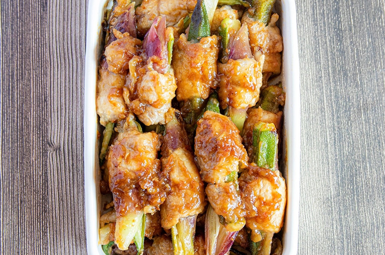 白いプレートに盛られた、オクラとみょうがが肉に巻かれた料理。ボリュームたっぷりで、食欲をそそる見た目。