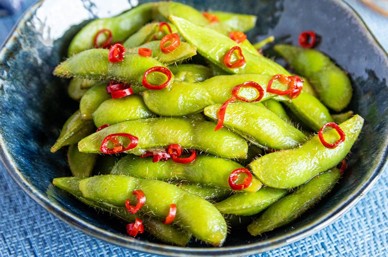 皿に盛られた枝豆に唐辛子の輪切りがトッピングされている。食事シーン。