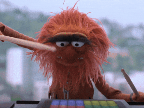 Muppet character Animal enthusiastically plays a digital drum kit, showcasing energetic drumming skills