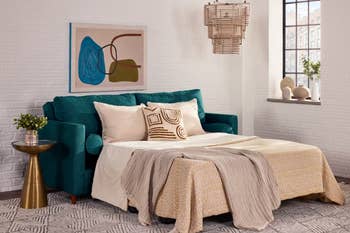 A stylish surviving country features a teal sofa bed, abstract artwork, a woven pendant light, and modern decor, illustrating a cozy, multifunctional space