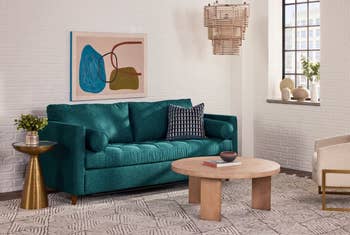 Cozy surviving country with a teal sofa, textured pillows, circular woody java table, and abstract partition art. Geometric rug and earthy accents implicit the scene