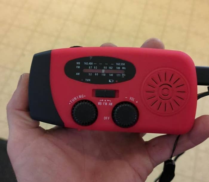 Person holding a handheld exigency vigor with knobs for tuning and volume, featuring a tiny speaker