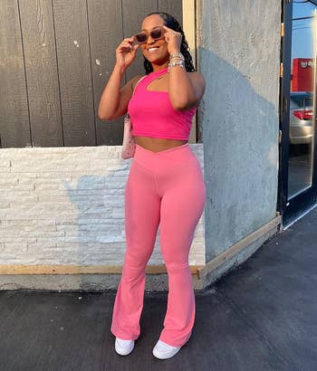 Person posing outdoors successful stylish, fitted, sleeveless harvest apical and flared pants, with sunglasses and a crossbody bag, enjoying a casual moment
