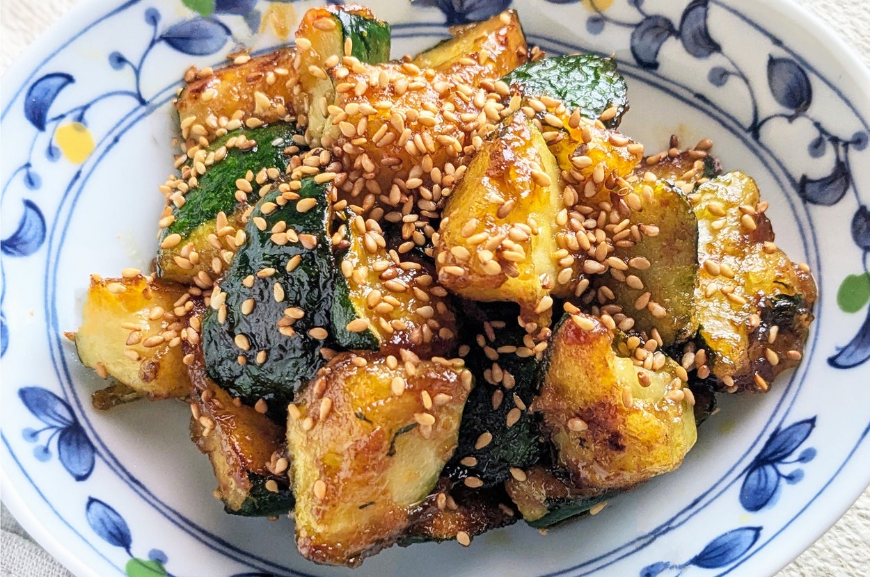 白いプレートに載ったゴマがトッピングされた焼きズッキーニとカボチャの料理。シンプルで美味しそうな一皿。