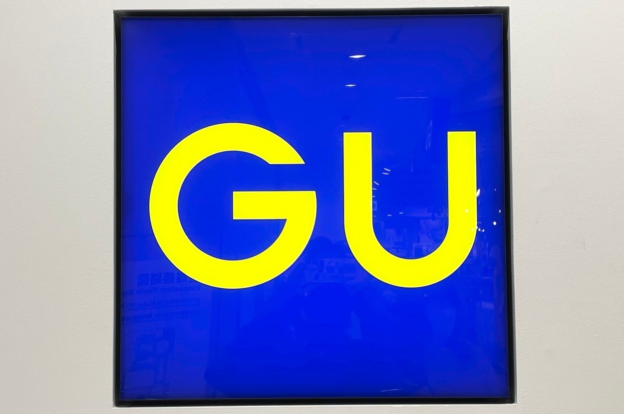 A store sign with the letters "GU" in bold font inside a square frame, presumably indicating the store's name