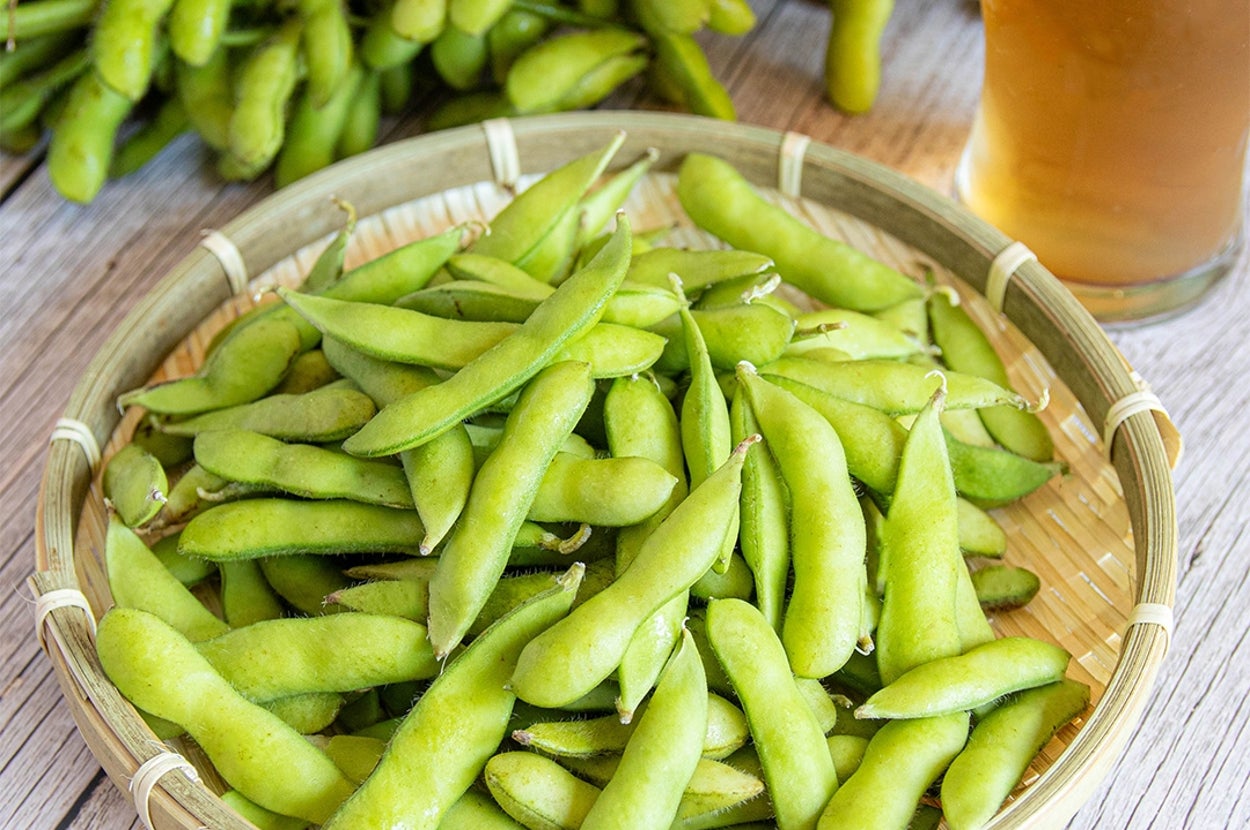 枝豆が竹のざるに載せられ、ビールが横に置かれている。