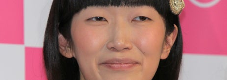 女性がカジュアルな花柄の服を着て微笑んでいる。髪にキラキラしたヘアクリップをつけている。