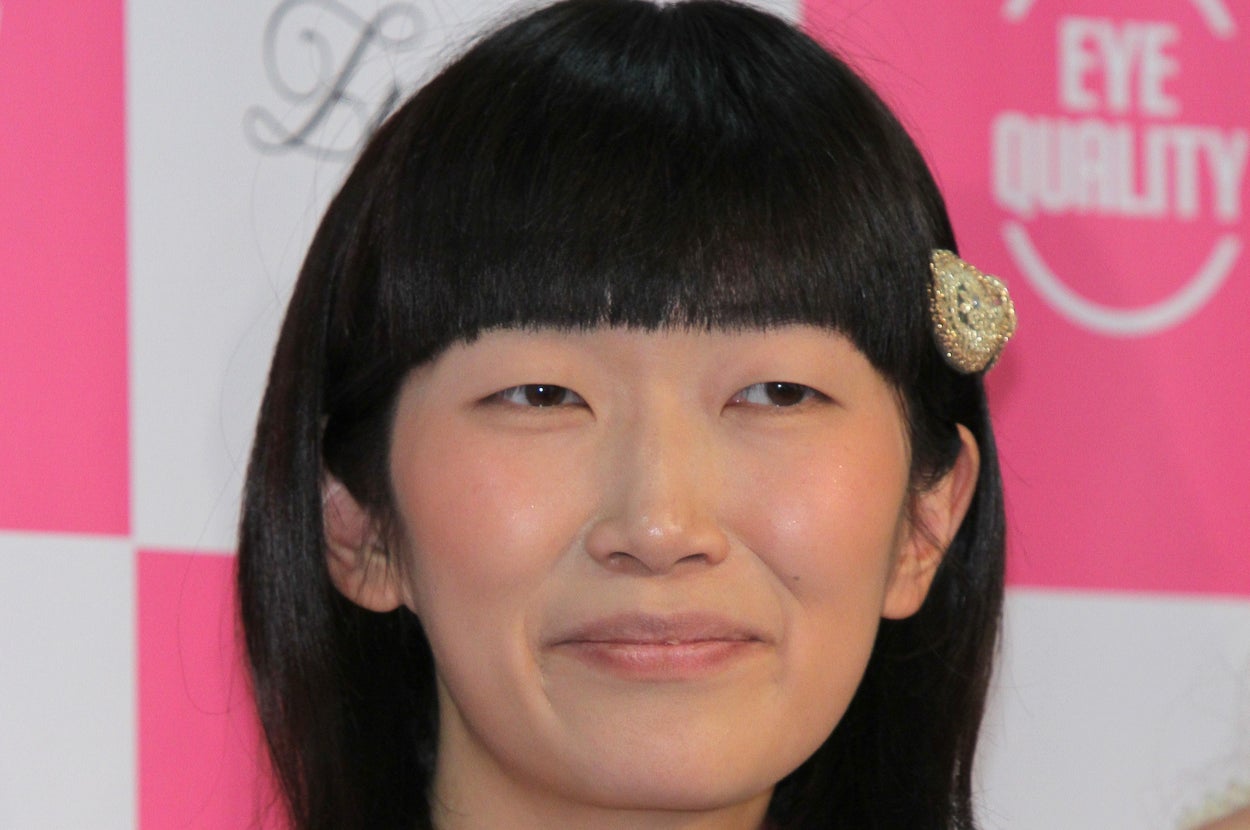 女性がカジュアルな花柄の服を着て微笑んでいる。髪にキラキラしたヘアクリップをつけている。