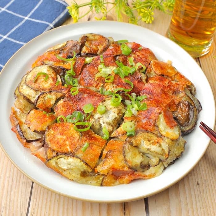 ナス料理が皿に盛られています。上には細かく切ったネギがトッピングされています。