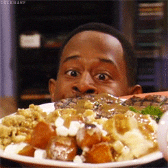 Person eagerly looks at a large plate of Thanksgiving food, featuring turkey, gravy, sweet potatoes, and stuffing