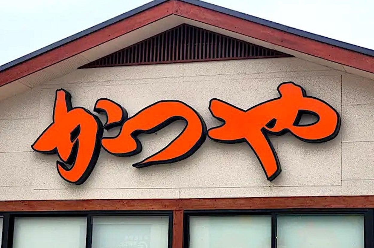 Sign with stylized Japanese characters on a building facade. The building has a minimalist design