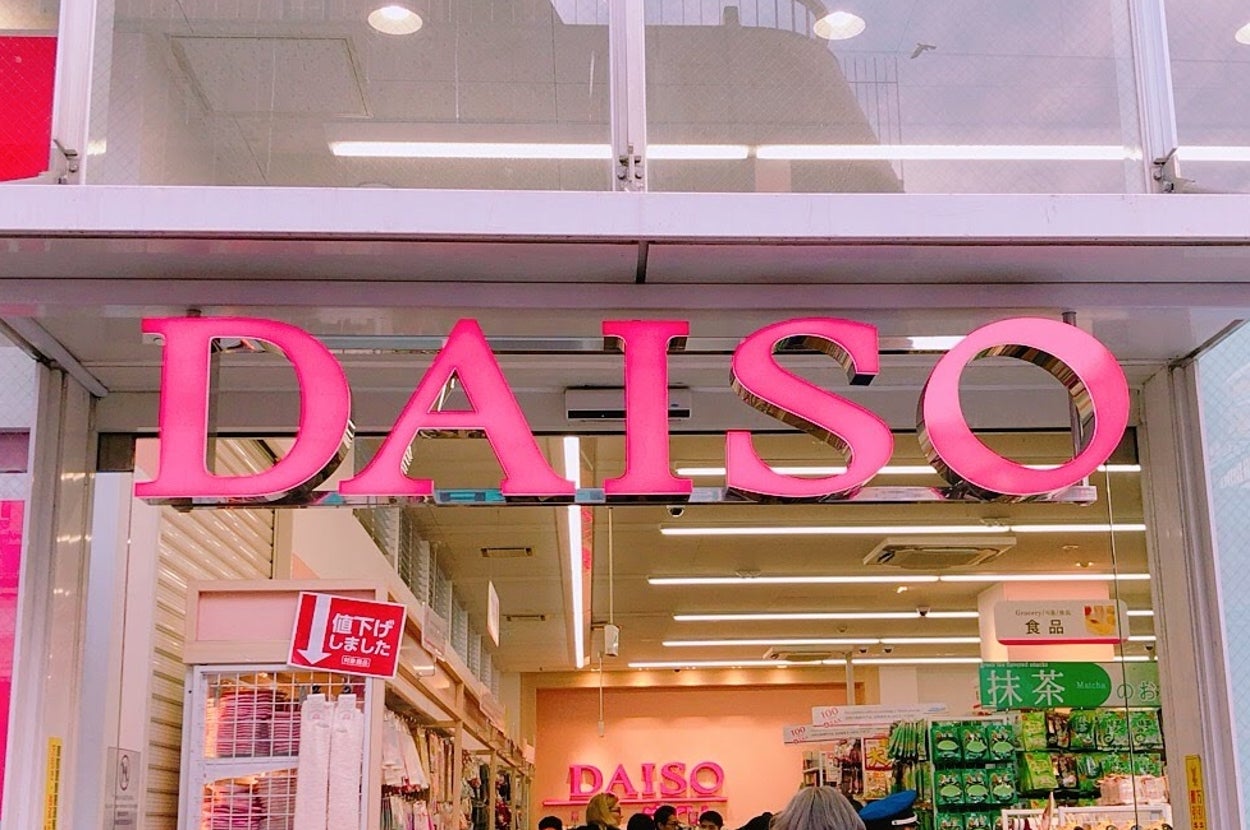 ダイソー店舗の入口。多くの買い物客が出入りし、商品が並ぶ内部が見える。