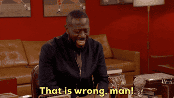 A person in a room laughs heartily while seated at a table. Subtitles read: &quot;That is wrong, man!&quot;