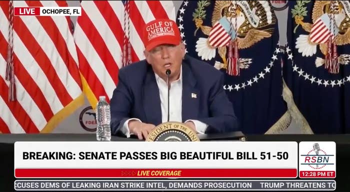 Person in a hat sits at a table with a presidential seal, speaking at a press conference. Banner text: "Senate passes big beautiful bill 51-50."