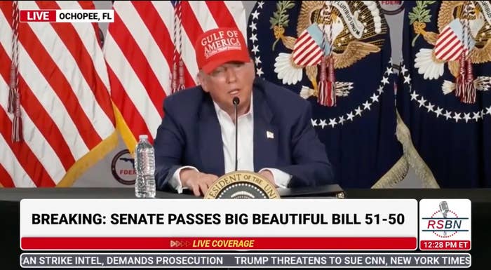 A person wearing a red "Gulf of Mexico" cap speaks at a press conference. Breaking news ticker: Senate passes big beautiful bill 51-50