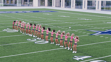 Cheerleaders perform a synchronized dance routine on a football field