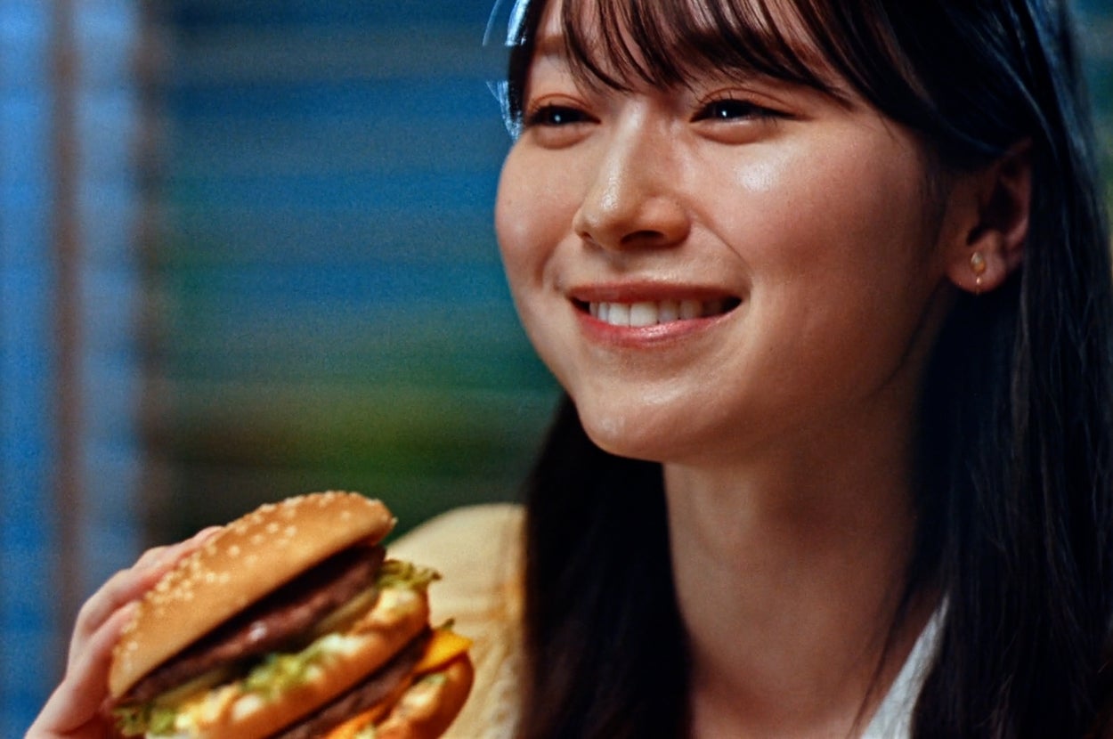 女性がハンバーガーを持ち、微笑んでいます。