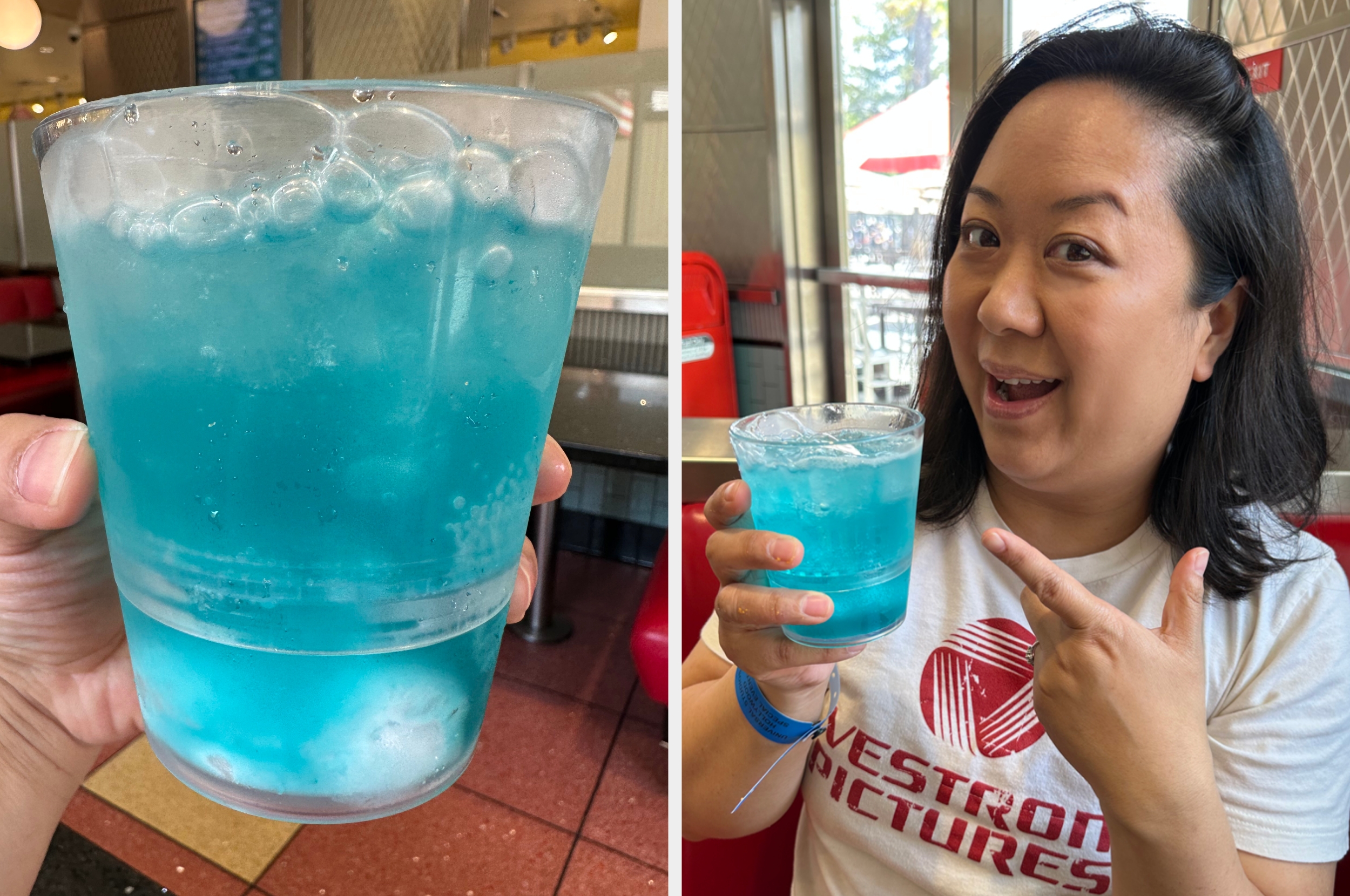 Person holding a blue beverage, smiling and gesturing to it inside a diner