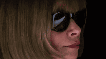 A person wearing dark sunglasses appears to be watching something intensely, with a focused expression