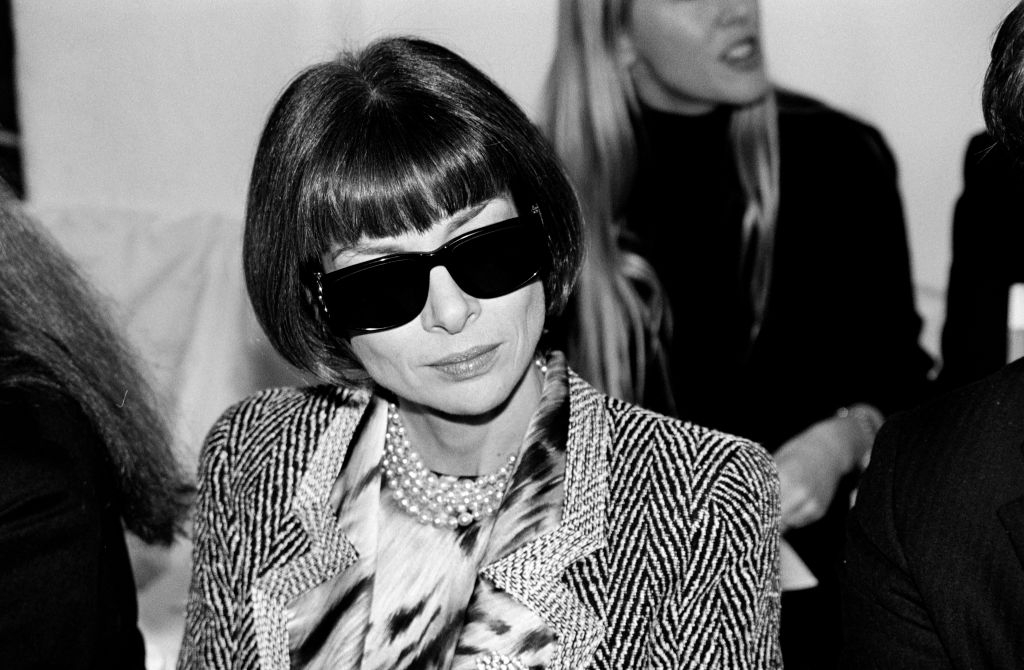 Person wearing large sunglasses and stylish outfit with a patterned jacket