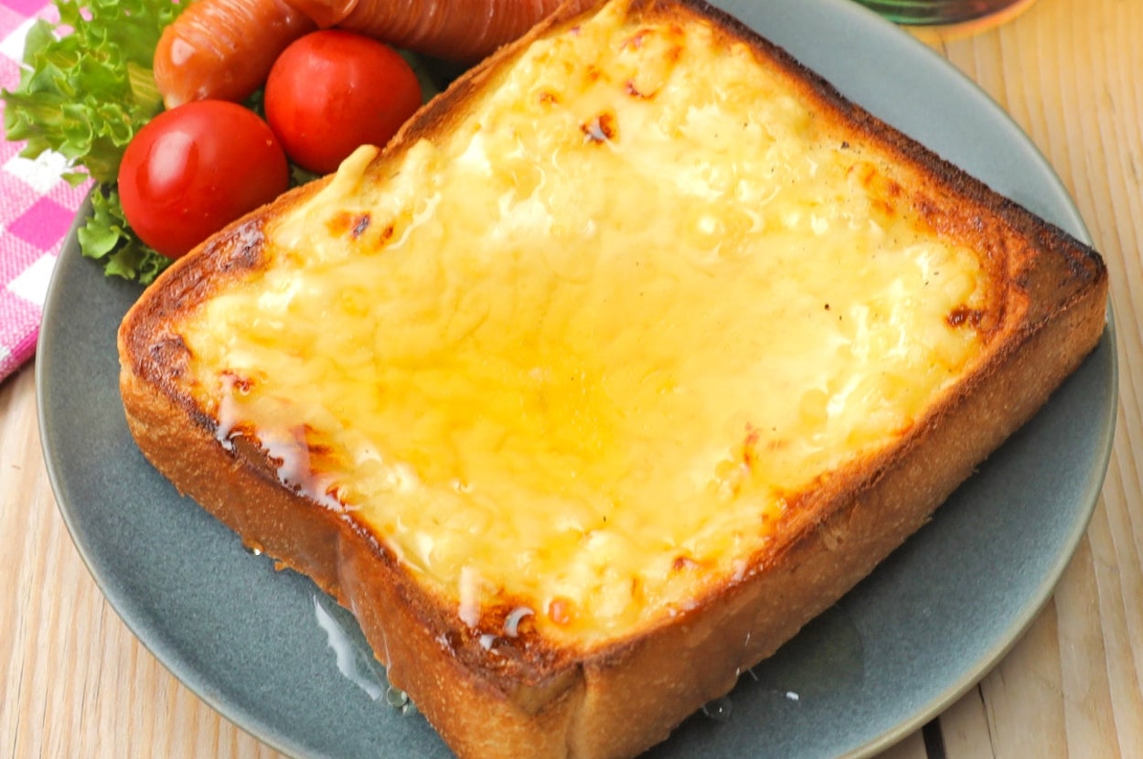 チーズトーストとソーセージ、レタス、トマトが皿に盛られ、飲み物がそばにある朝食プレート。